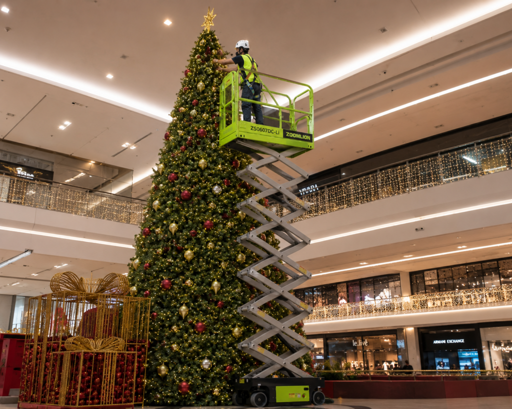 Plataforma tesoura eleva operador que decora uma grande árvore de Natal no interior de um shopping.